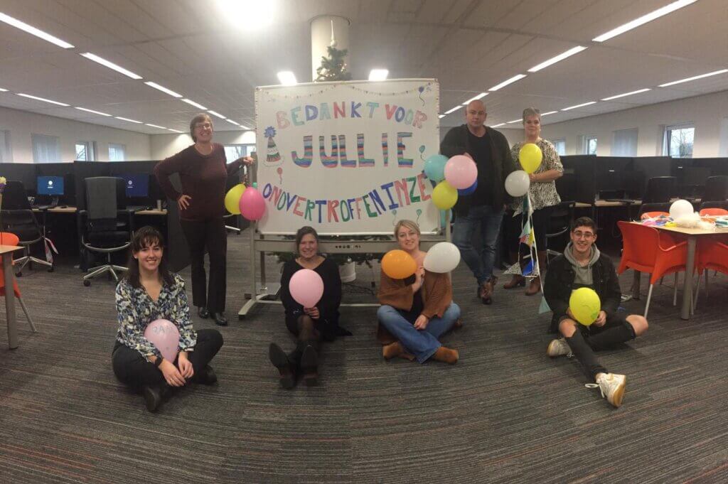Op de foto onze medewerkers. Een feestelijke foto met een bord dat zegt 'bedankt voor jullie onovertroffen inzet!'.