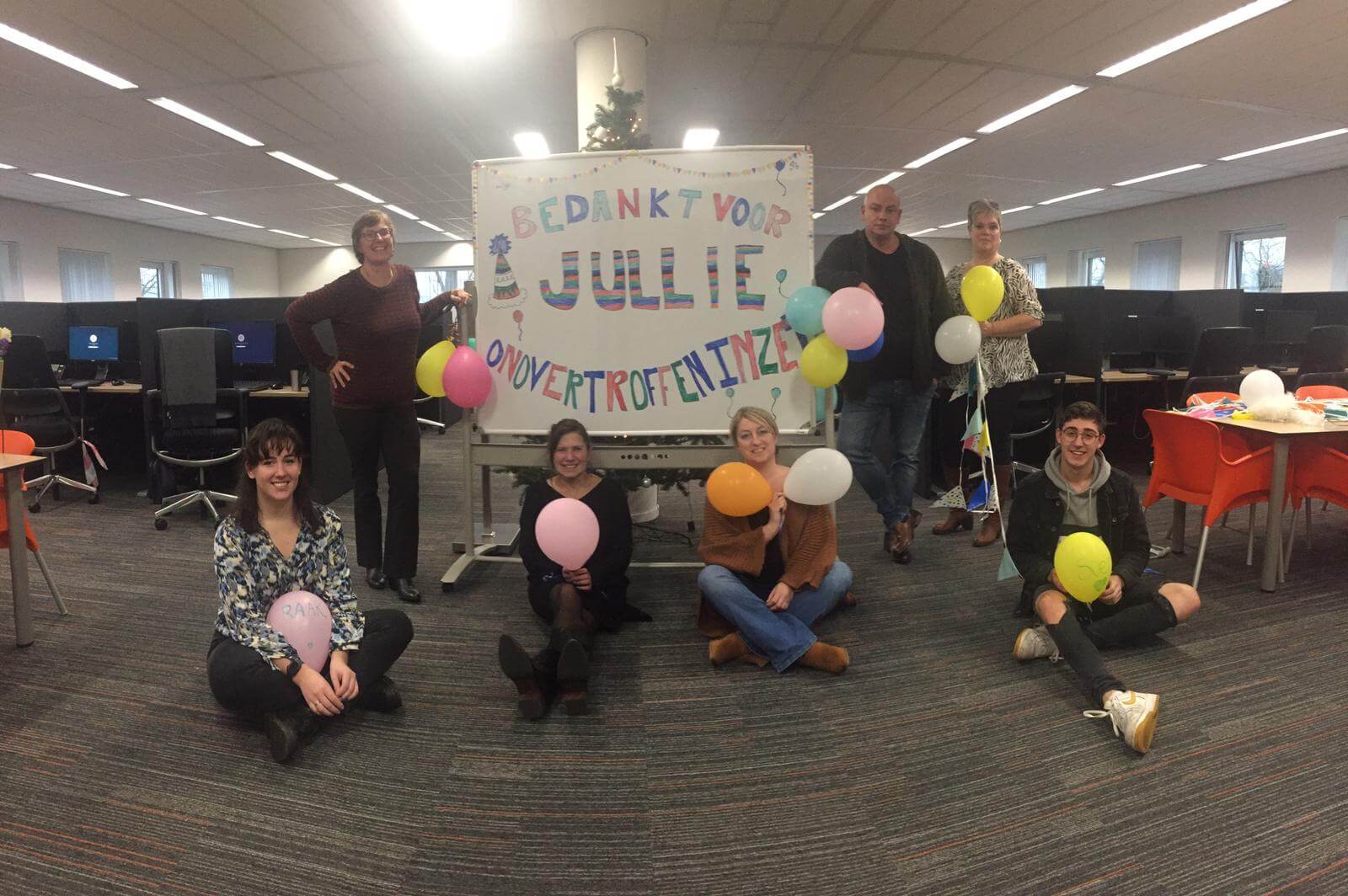Op de foto onze medewerkers. Een feestelijke foto met een bord dat zegt 'bedankt voor jullie onovertroffen inzet!'.